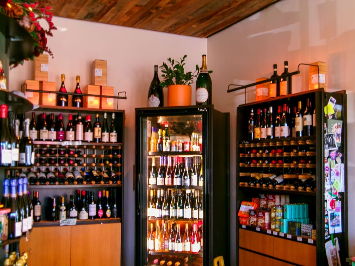 A glass-fronted wine refrigerator holding bottles on wooden shelves