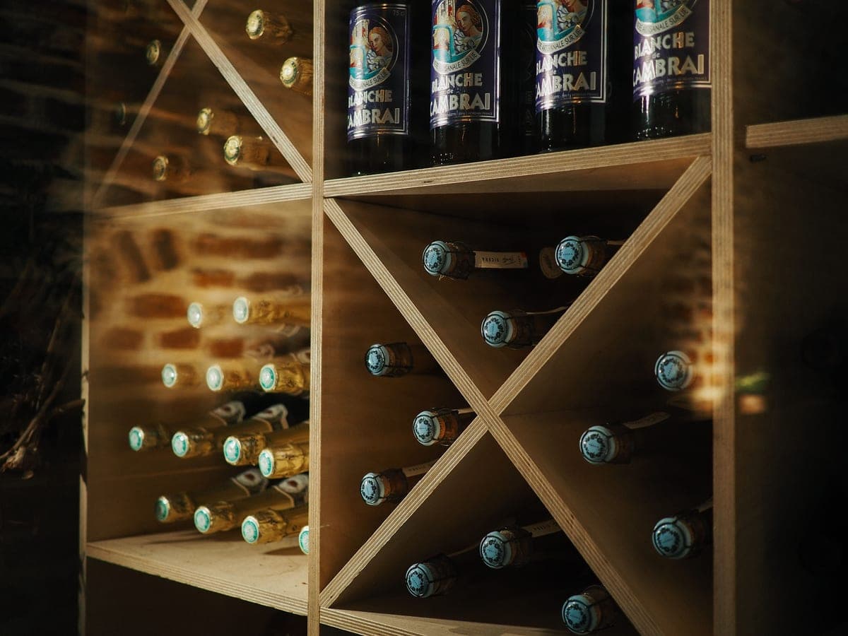 A wooden wall-mounted wine rack holding bottles horizontally