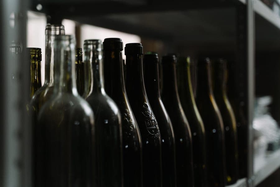 A wine bottle on a dark shelf in a still, quiet room